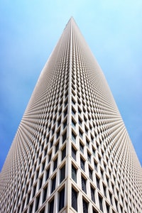 Low-angle shot of a tall white building pointing to a blue sky